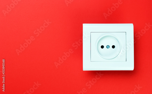 White plastic power socket on red background. Wall with copy space. Minimalism.