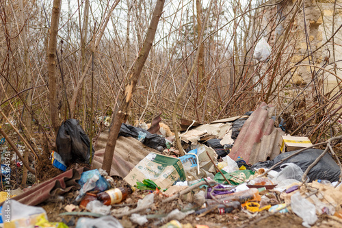 Pile of garbage among trees and bushes. Environmental pollution concept.