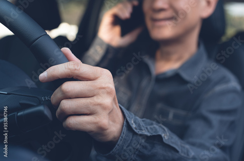 Smiling asian business man using mobile phone calling while driving a car