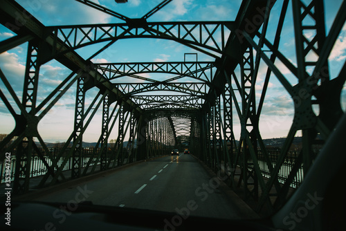 Tunel of a dark metal bridge for cars over a river