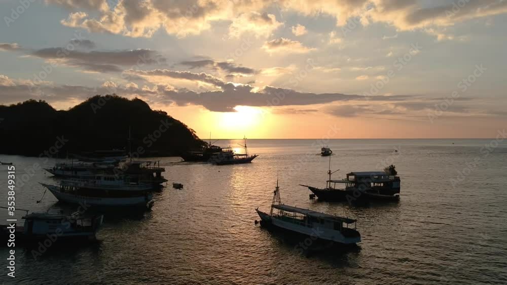Aerial drone, sunrise/sunset clip of boat port/harbor town, fishing boats and wooden jetty in calm ocean surrounded by small islands, Indonesia Aerial drone, sunrise/sunset clip of boat port/harbor town, fishing boats and wooden jetty in calm ocean surrounded by small islands, Indonesia