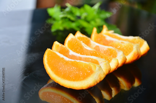 Green parsley and orange in slices on a black glass