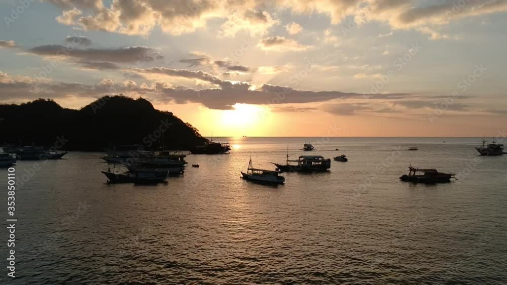 Aerial drone, sunrise/sunset clip of boat port/harbor town, fishing boats and wooden jetty in calm ocean surrounded by small islands, Indonesia Aerial drone, sunrise/sunset clip of boat port/harbor town, fishing boats and wooden jetty in calm ocean surrounded by small islands, Indonesia