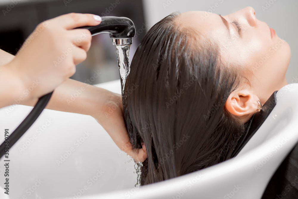 Fototapeta premium Shampooing hair in spa beauty salon of young brunette woman, hairdresser caring for client