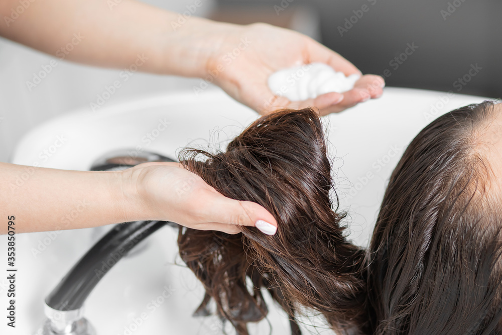 Naklejka premium Beautiful brunette woman getting hair wash in beauty salon
