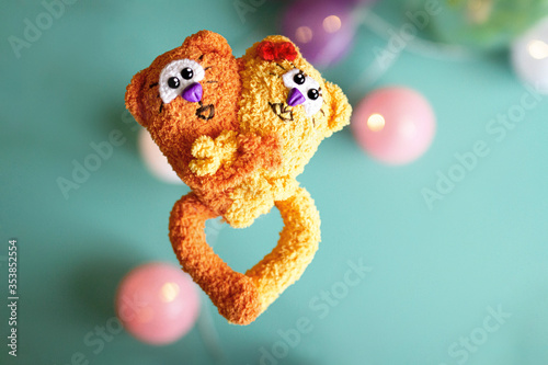Foto toy knitted two red and yellow love cats made of wool against background of gree