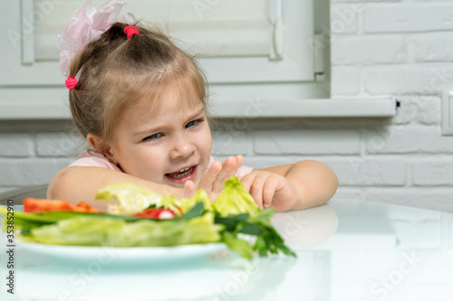 Foto a little girl emotionally pushes away a plate of offered vegetables