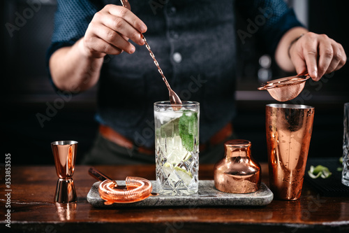 Professional bartender pouring and preparing mojito with lime at bar counter. Details of mixology