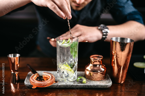 Professional bartender preparing and mixing cocktails at bar counter. Mojito cocktail served in restaurant, pub and bar. Long drink cocktail concept