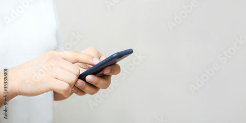 A person is holding a phone and tapping the screen on a white background with copy space. Concept of lifestyle business and Internet technologies in the office