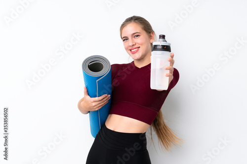 Sport teenager girl over isolated white background with sports water bottle and with a mat