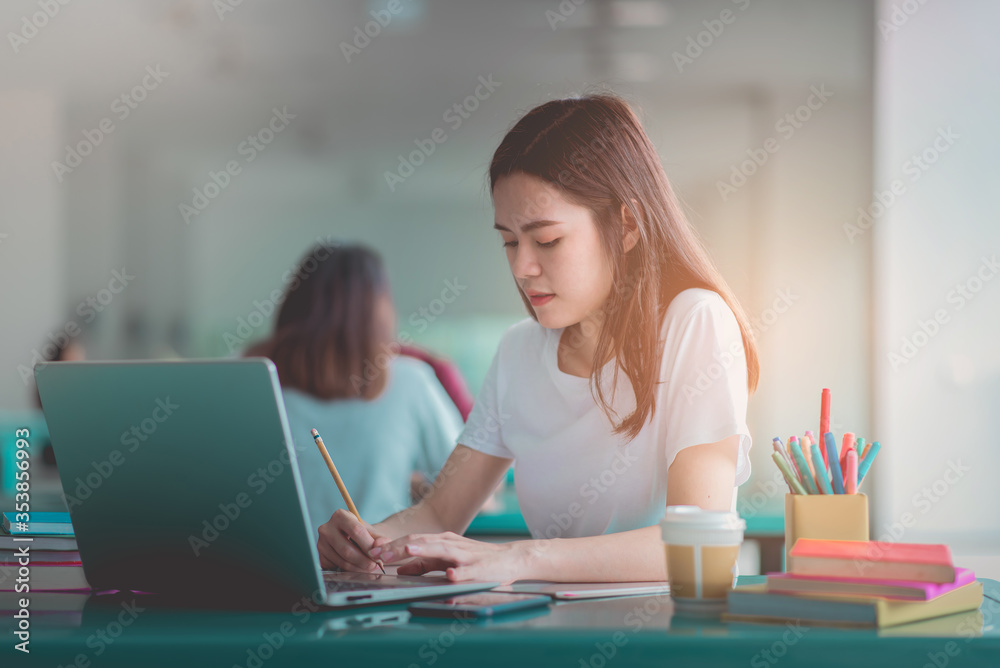 A young woman reading and writtening book with many books, happy education university concept. A young woman reading and writtening book with many books, happy education university concept.