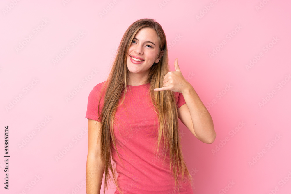 Teenager blonde girl over isolated pink background making phone gesture Teenager blonde girl over isolated pink background making phone gesture