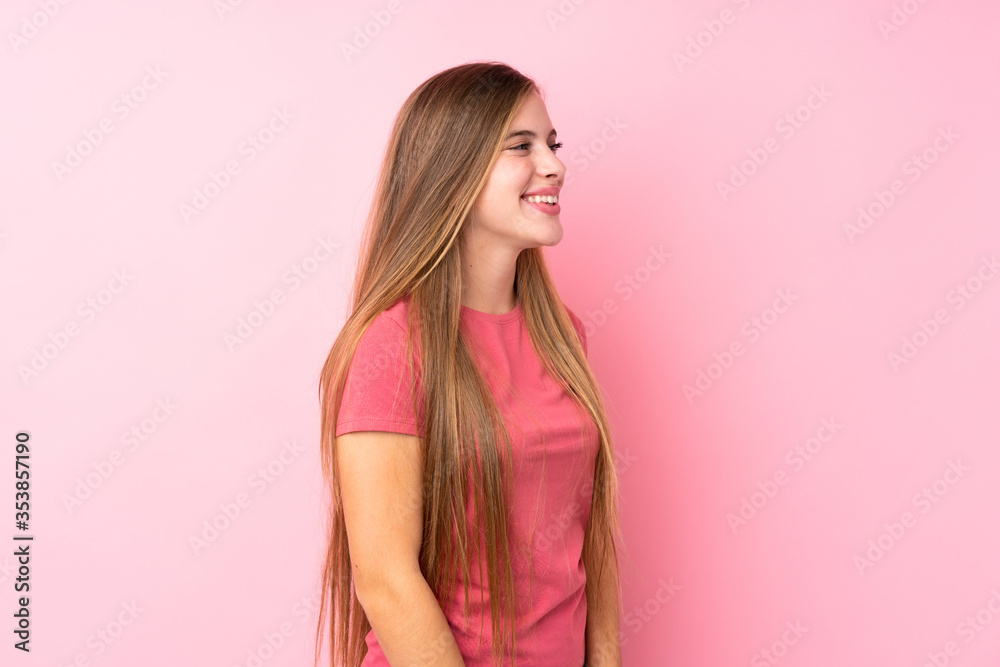 Teenager blonde girl over isolated pink background looking to the side Teenager blonde girl over isolated pink background looking to the side
