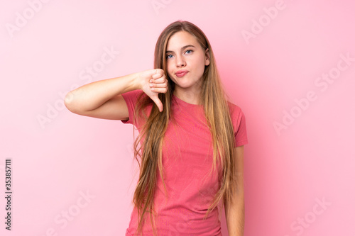 Teenager blonde girl over isolated pink background showing thumb down sign