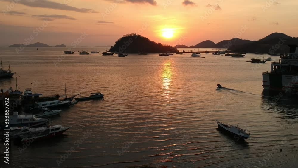 Aerial Drone, sunset/sunrise clip of boats floating on water in busy harbor, calm ocean, islands in background, Indonesia Aerial Drone, sunset/sunrise clip of boats floating on water in busy harbor, calm ocean, islands in background, Indonesia