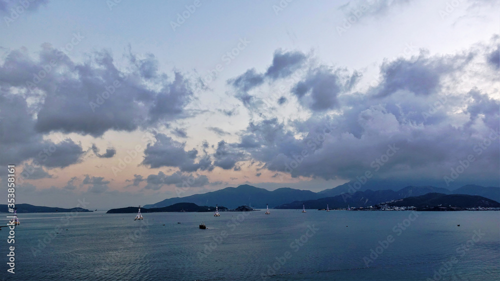 Cableway in Vietnam. In the evening, on the calm surface of the bay there are many luminous supports of the cable car. Picturesque clouds on the sky. In the distance are the silhouettes of mountains.