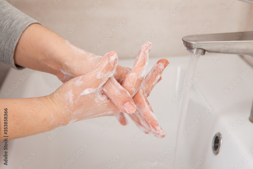 Fototapeta premium Proper hand washing as a prevention of coronavirus. Close-up of women's hands in soap in the bathroom