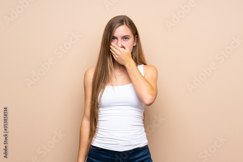 Teenager blonde girl over isolated background covering mouth with hands