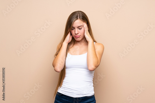 Teenager blonde girl over isolated background with headache