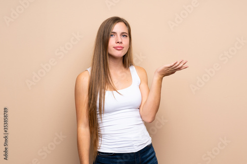 Teenager blonde girl over isolated background making doubts gesture