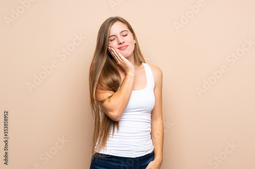 Teenager blonde girl over isolated background with toothache