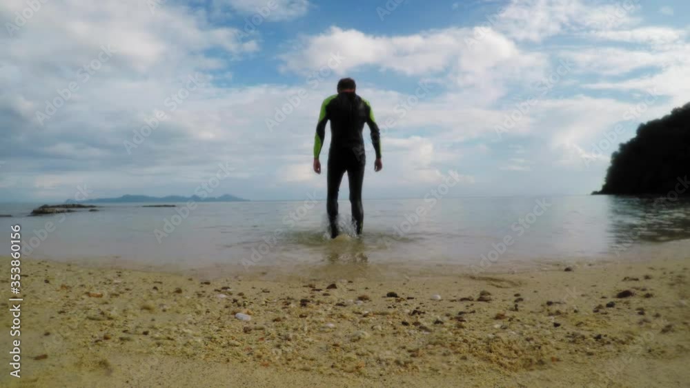 Caucasian male walks into the sea while his - low angle shot. Caucasian male walks into the sea while his - low angle shot.