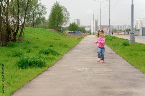 little girl runs down the street in summer and laughs