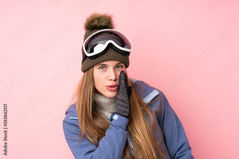 Skier teenager girl with snowboarding glasses over isolated pink background whispering something Skier teenager girl with snowboarding glasses over isolated pink background whispering something