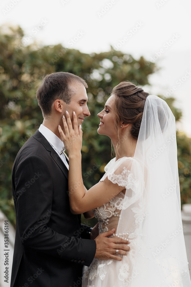 Bride and groom at wedding Day walking Outdoors on castle territory in summer.Bridal couple, Newlywed woman and man embracing with love. People happy and smile.Happy couple in love look at each other