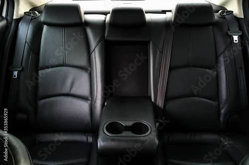 Back passenger seats in modern luxury car, frontal view, black perforated leather, Luxury car inside. Interior of prestige modern car. Comfortable leather seats. 