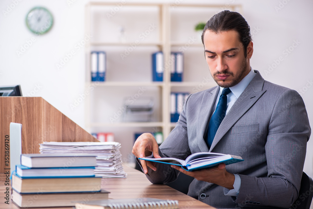 Young male businessman reading books at workplace Young male businessman reading books at workplace
