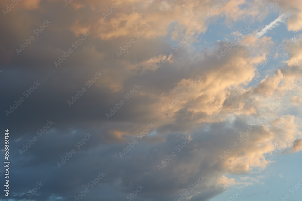 Thick Cumulus clouds lit on one side by the setting sun