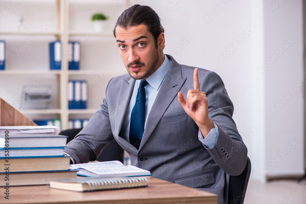 Young male businessman reading books at workplace Young male businessman reading books at workplace