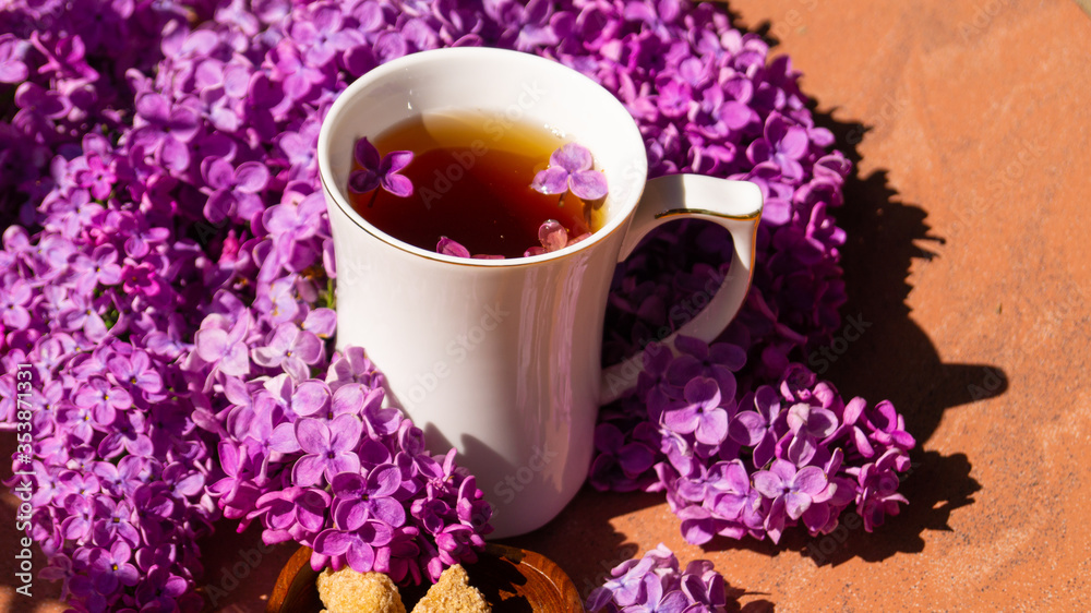 white porcelain cup with tea and among flowering branches of lilac white porcelain cup with tea and among flowering branches of lilac