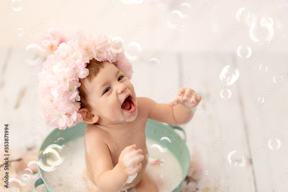 a cheerful happy girl one year bathes in a bath with foam, catches soap bubbles a cheerful happy girl one year bathes in a bath with foam, catches soap bubbles