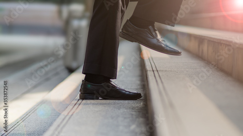 Close-up of businessman's black leather shoes walking up the steps. Business concept