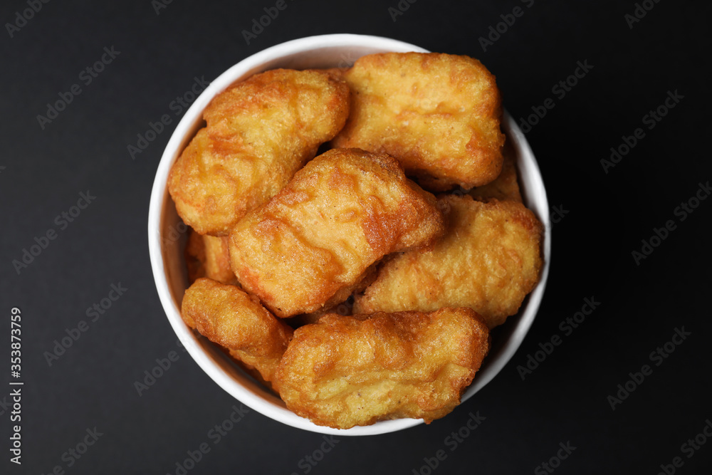 Bucket with delicious chicken nuggets on black background, top view Bucket with delicious chicken nuggets on black background, top view