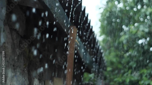 raindrops falling from the roof on a background of a tree with summer rain leaves
