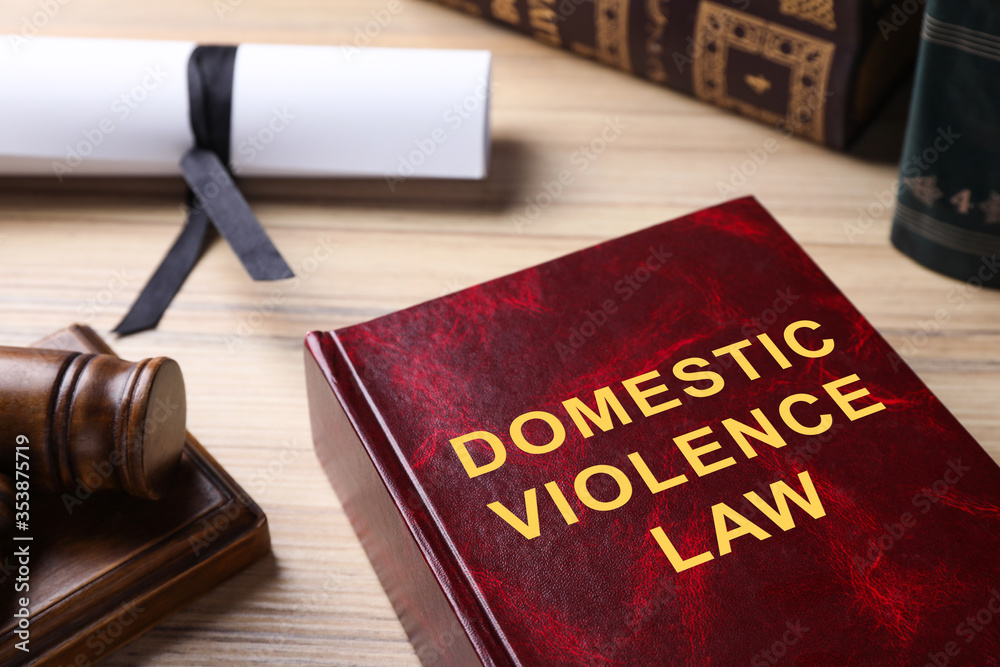 Domestic violence law book on wooden table, closeup Domestic violence law book on wooden table, closeup