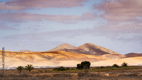 Morgensonne scheint auf Hügelkette im Hintergrund mit Schatten auf dem Vordergrund in wüstenartiger Umgebung
