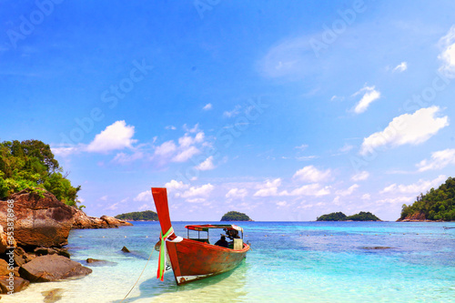 A wooden boat at the beach with blue sea, white cloud in blue sky, nobody and more space for copy paste
