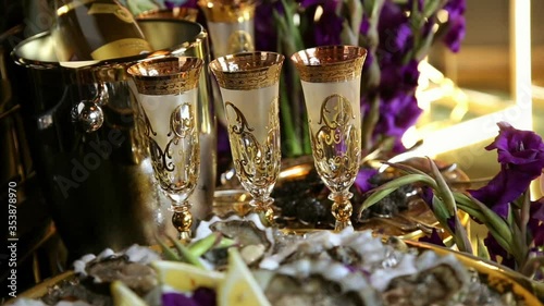gold wine glasses a bottle of champagne in a silver bucket lilac gladioli for party decoration in a Golden style