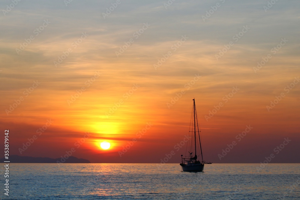 The sun set at the sea with silhouette  of sailboat in twilight sky background