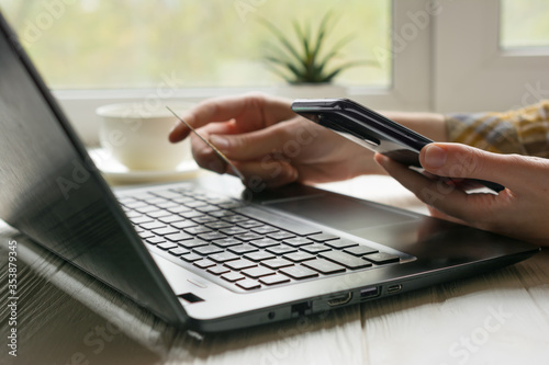 Online shopping from home office with credit card, phone and black laptop