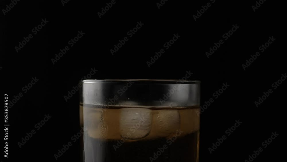 Spinning ice cubes in glass with whisky, close up, slow motion Spinning ice cubes in glass with whisky, close up, slow motion