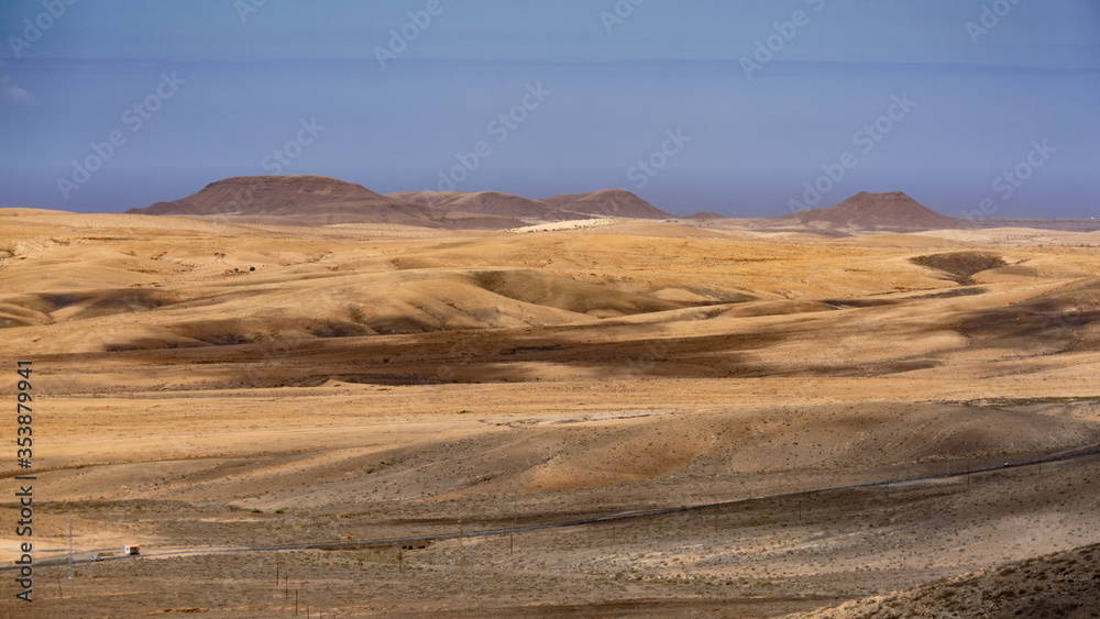 Ziehende Wolken werfen Schatten über eine Wüstenlandschaft mit Blick auf eine ferne Küste Ziehende Wolken werfen Schatten über eine Wüstenlandschaft mit Blick auf eine ferne Küste