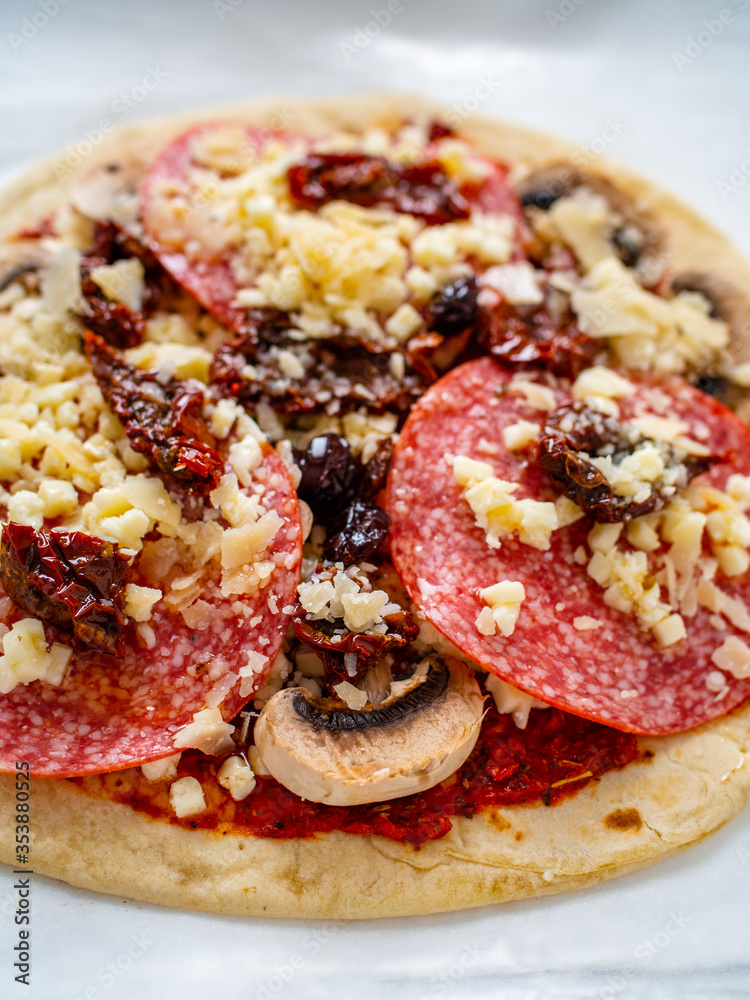 Uncooked margherita pizza on baking paper
