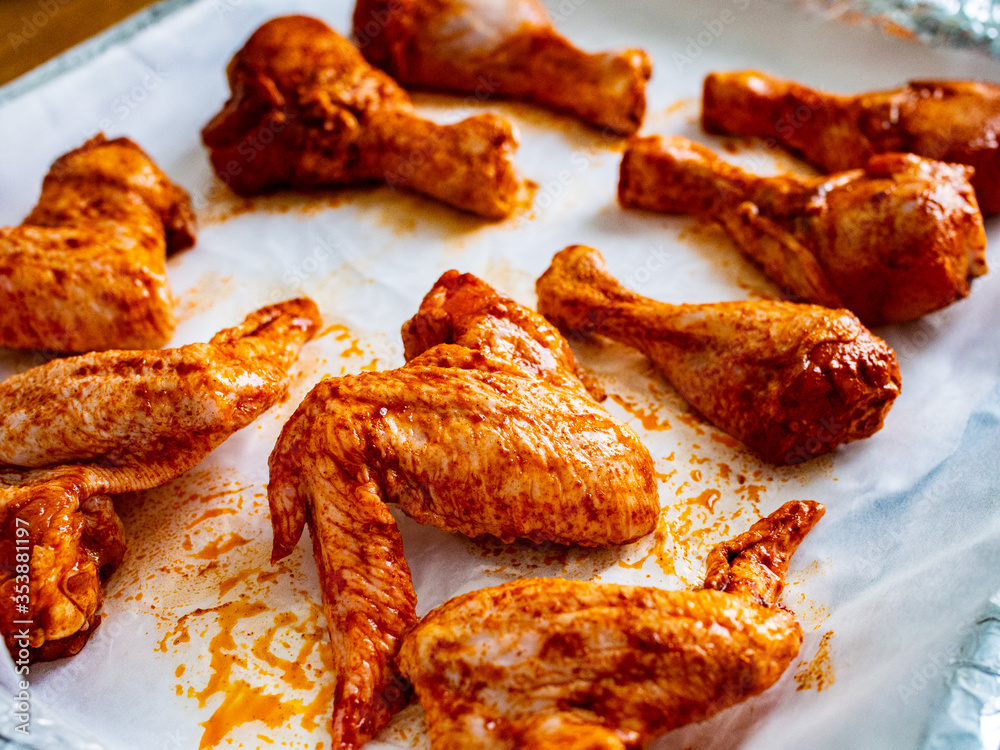 Raw chicken drumsticks and wings on baking paper Raw chicken drumsticks and wings on baking paper