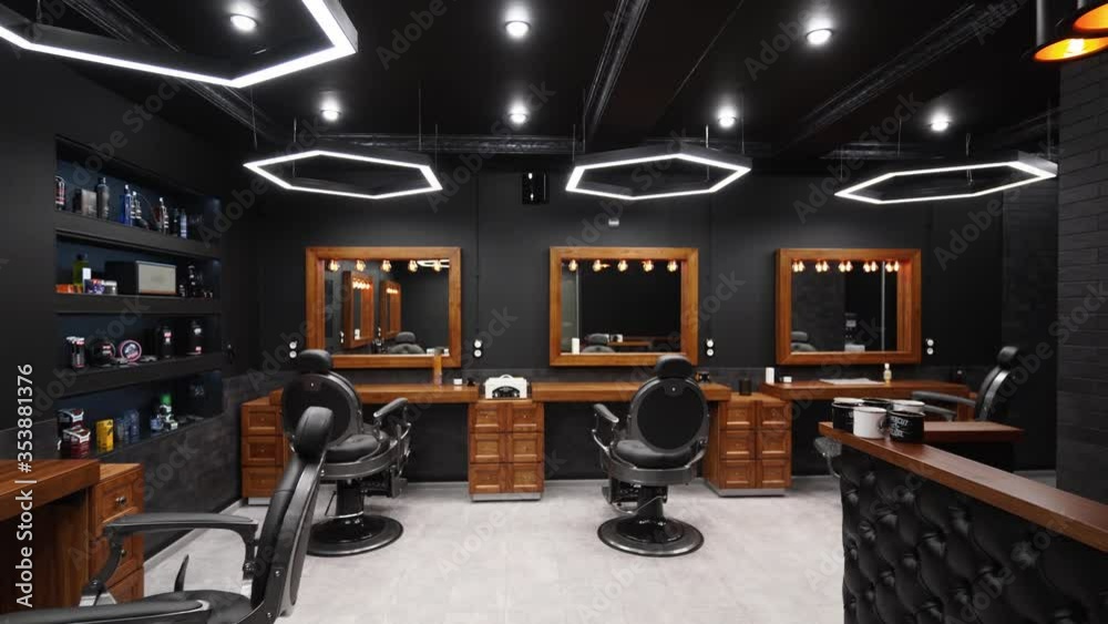 Vintage barbershop interior - movement along the chairs, wooden tables and mirrors. Stylish hair studio indoors. Stylish beauty salon design with modern lighting and lamps.